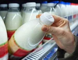 Consumer pulling milk bottle off shelf